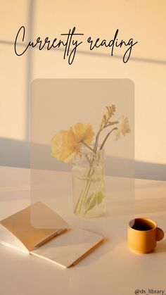 a vase with yellow flowers sitting on top of a white table next to a book