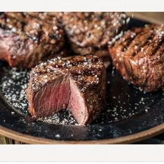 steaks on a plate with salt and pepper sprinkled on the top, ready to be eaten