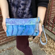 "A large Wristlet with a detachable strap so it can become a Clutch! This is a very unique piece of Functional Fiber Art- it's Sky Blue hand painted and Felted Wool appliquéd with sparkly textured designer Yarn ,a touch of Batik,AND adorned with glass and resin beads. Sky Blue Italian Leather strap and tassel zip charm ( with a Blue Swarovski Crystal Rivet) are the finishing touches . This is a fancy handbag for special occasions or for everyday. It easily fits the largest phone and a whole lot Fancy Handbags, Felt Tote Bag, Felt Tote, Resin Beads, Felted Wool, Mini Purse, Italian Leather, Art Gift, Wool Felt