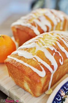 there is a loaf of bread with icing on it and oranges in the background