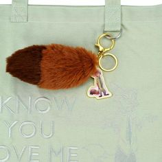 a keychain with a fur ball hanging from it's side and the words know you love me on it