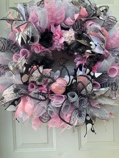 a pink and black wreath is hanging on the front door