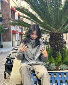 a woman sitting on top of a blue bench next to a palm tree and potted plant