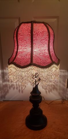 a lamp that is on a table with a red shade hanging from it's side