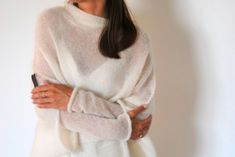 Off white poncho, ivory mohair pullover, bridal mohair cardigan, soft mohair silk sweater, wedding soft sweater, handmade knitted pullover This women's off white poncho is of loose knit, versatile, easy to wear and to look after, comfortable. Knitted shawl poncho made of pure mohair-silk is a perfect choice for any occasion. It can be worn as a summer scarf, beach cover up, an evening shawl or an oversize sweater. Knitted sleeves are separate. Can be used as a knit sleeve or as a separate wrist. Elegant Oversized White Sweater, Chic White Mohair Sweater, Elegant White Soft Knit Sweater, Cozy White Mohair Sweater, Elegant Mohair Soft Knit Sweater, Elegant Soft Knit Mohair Sweater, Elegant White Hand Knitted Sweater, Elegant White Mohair Sweater, Wedding Sweater