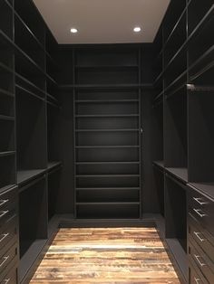 an empty walk - in closet with wooden flooring and black walls, along with dark shelving