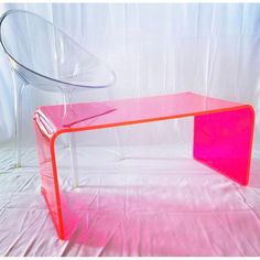 a pink table sitting on top of a white cloth covered floor next to a plastic chair