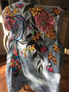 the back of a jean jacket with embroidered flowers on it