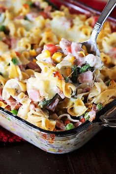 a casserole dish filled with pasta, ham and vegetables on a red cloth