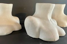 three white vases sitting next to each other on a black counter top in front of a gray wall