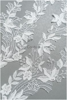 white lace on grey fabric with flowers and leaves in the center, as well as an image