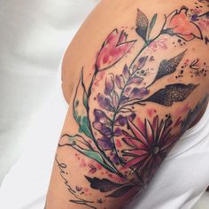 a woman's arm with flowers and leaves painted on the back of her shoulder