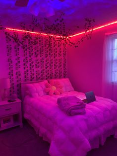 a bed in a room with purple lighting and decorations on the wall above it, along with a laptop computer