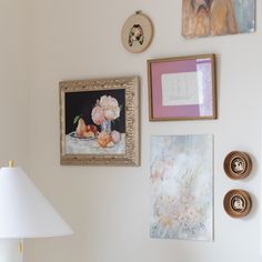 there are pictures on the wall with flowers and fruit in them, along with two lamps