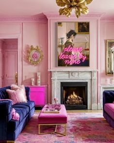 a living room with pink walls and blue couches in front of a fire place