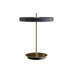 a black and gold table lamp with a round shade on the top, in front of a white background