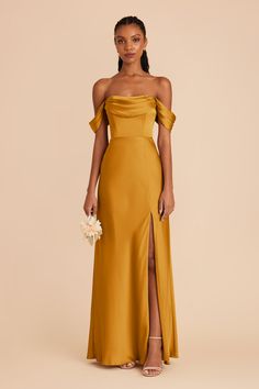 a woman wearing an off the shoulder mustard colored dress with thigh high slit and side split