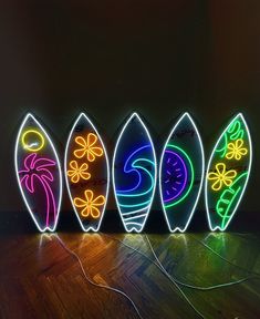 four surfboards are lit up with neon lights