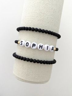 one name bracelet made with 4mm black matte beads with 14k gold accent beads on either side of the name bracelets are made on a durable stretch elastic cord please refer to our sizing guide before purchasing Word Bracelets, Rainbow Writing, Name Bracelets, Word Bracelet, White Rainbow, Stackable Bracelets, Letter Beads, Bracelet Black, Name Bracelet