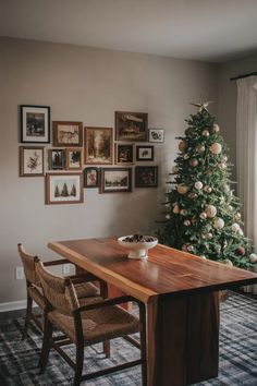 a christmas tree in the corner of a room with pictures on the wall above it