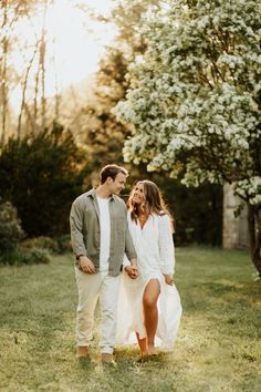 a man and woman are walking through the grass