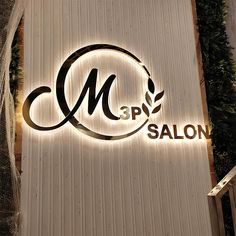 the logo or sign for a salon is lit up with lights and greenery behind it