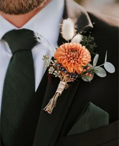 a man wearing a suit and tie with an orange flower boutonniere on his lapel