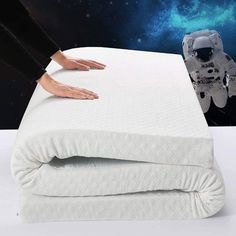 an image of a person reaching for the mattress on top of two sheets that are folded up