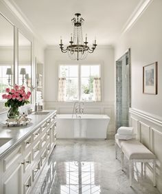 an instagramted photo of a white bathroom with chandelier and bathtub