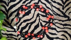 a close up of a necklace on a zebra print surface with plants in the background