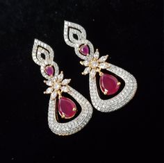 "These American Diamond earrings set has an excellent finish and gives out an exquisite sense of style. The gold covering Semi-precious Ruby, Emerald Danglers have a high-quality diamond-sparkle finish on the earrings. If you are looking for an amazing Fashion Jewelry set for special occasions such as Anniversary, Engagement, Party, Wedding, or for gifting, then your search ends here. Earring Length: 1.5\", Earring Width: 0.5\" , Weight of Single Earring: 0.570 Oz / 16gm * Packed in a box, Ideal Celebration Diamond Accent Drop Earrings, Celebration Drop Earrings With Diamond Accents, Red Diamond Earrings With Accents For Wedding, Dazzling Gold Earrings For Festive Occasions, American Diamond Earrings With Elegant Design For Gift, Dazzling Diamond Accented Earrings For Festive Occasions, Gold Plated Diamond White Drop Earrings, American Diamond Drop Earrings For Gift, Dazzling Festive Earrings With Diamond Accents