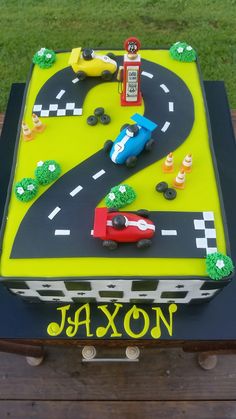 a birthday cake that is shaped like a race track and has cars on the road