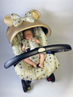 a baby in a car seat with a hat on it's head, holding onto a handlebar