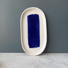 a white and blue plate sitting on top of a counter next to a gray wall