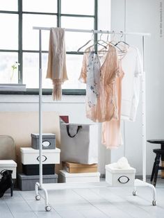 clothes are hanging on a rack in front of a window and other items sitting on the floor