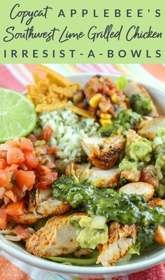 a white bowl filled with chicken, rice and guacamole on top of a colorful table cloth