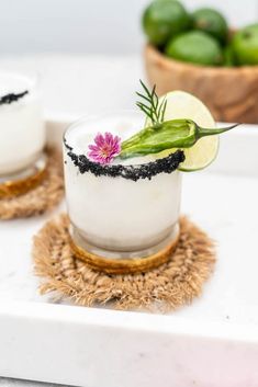 two small glasses filled with food on top of a white counter next to limes