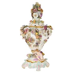 an ornate vase with flowers on it and a figurine in the bottom corner