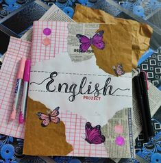 two notebooks with butterflies and the word english project written on them next to some pens