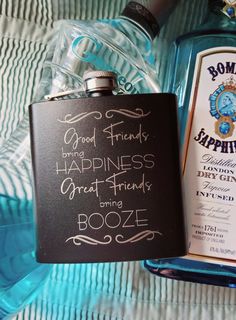 a flask and liquor bottle are sitting on a bed next to a sign that says good friends, happiness, great friends