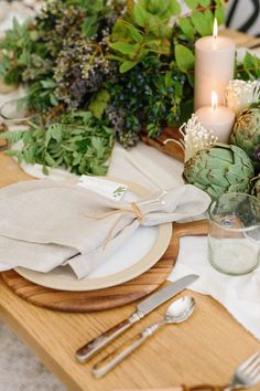 the table is set with silverware, candles and succulents on it