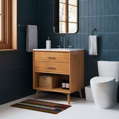 a white toilet sitting next to a wooden sink vanity in a blue tiled bathroom stall