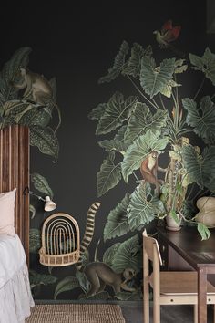 a bedroom decorated in black and green with tropical wallpaper, rattan chair, bed, table and desk