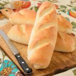 two loaves of bread sitting on top of a cutting board next to a knife