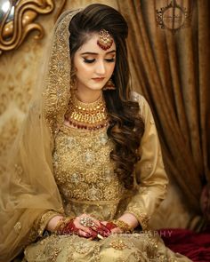 a woman in a bridal outfit sitting on a couch with her hands clasped to her chest