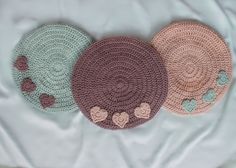 three round crocheted rugs sitting on top of a white sheet with hearts