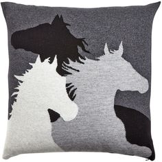 a pillow with two horses on it and one is black, white, and grey