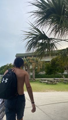 a man with no shirt is walking down the sidewalk carrying his surfboard behind him