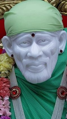 a close up of a statue with flowers in the foreground and an image of a man's face behind it