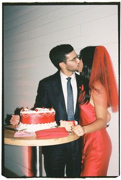 a man and woman standing next to each other in front of a cake